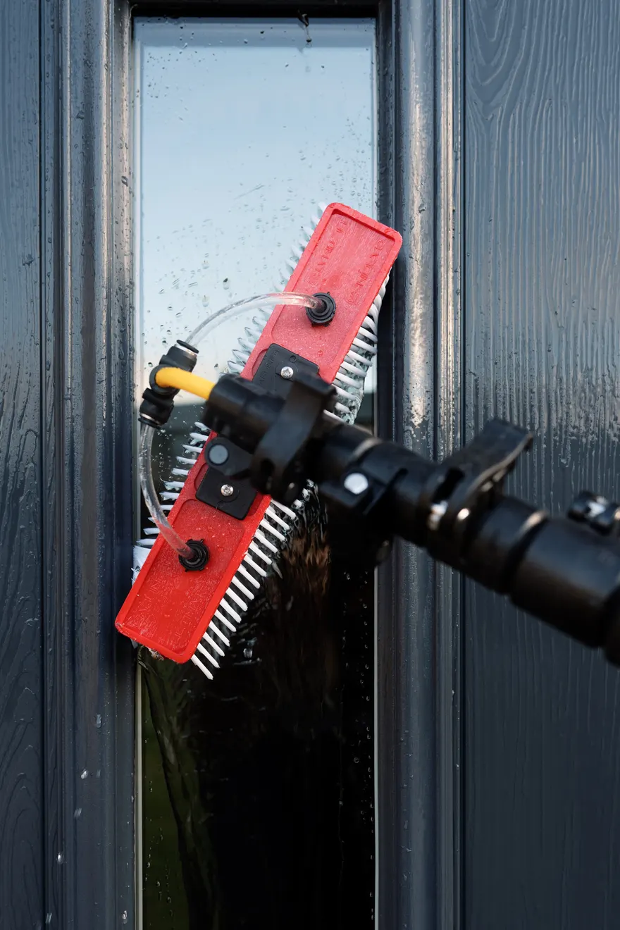 Close-up of a water-fed brush head cleaning dark glazing