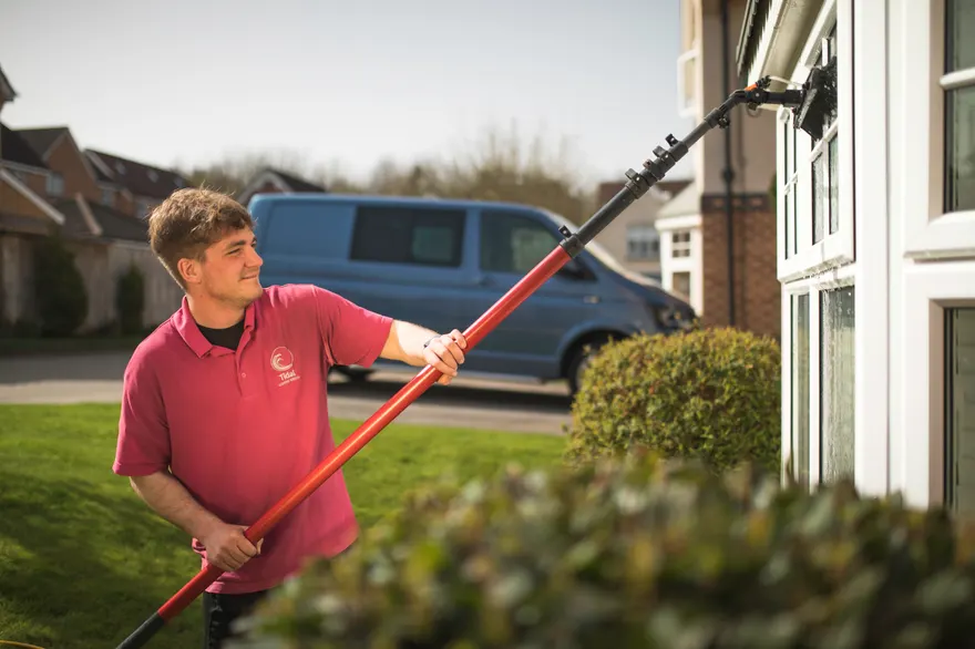 A Tidal window cleaner cleaning a bay window with a water-fed pole
