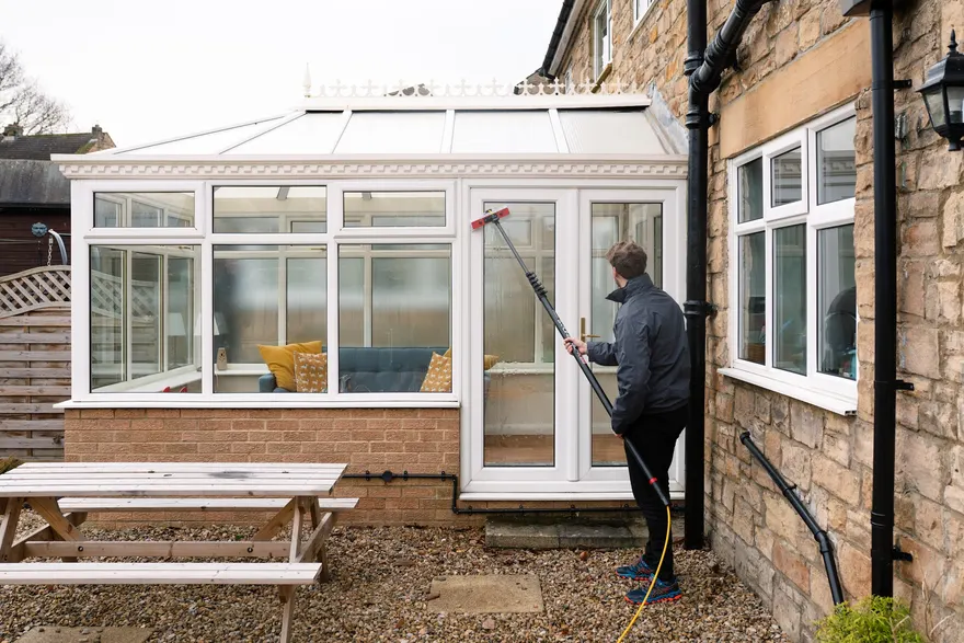 A conservatory being cleaned with a water-fed pole
