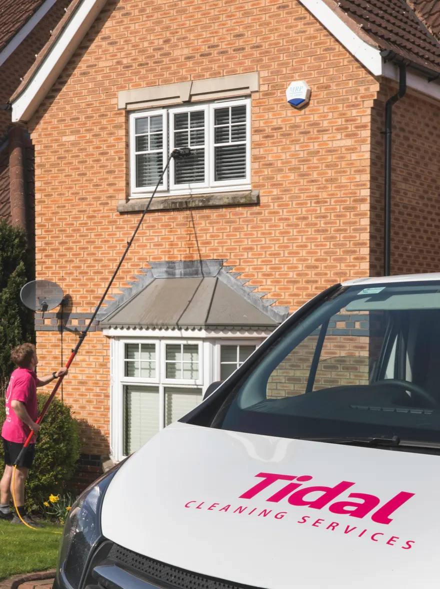 An upstairs window being cleaned with a pure-water pole, Tidal van parked in front